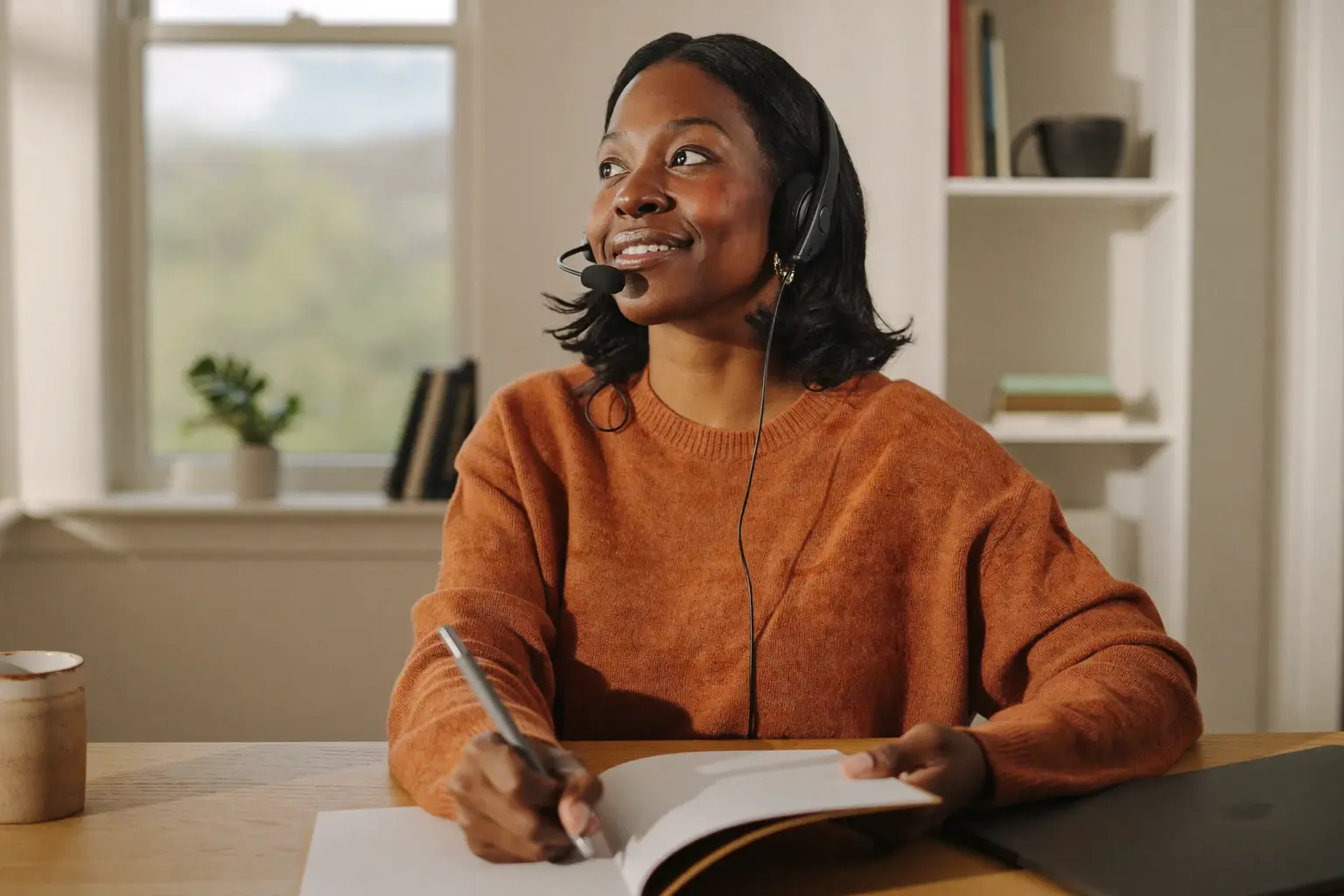 Dedicated assistant with a headset looking up from a paper planner at a tidy desk